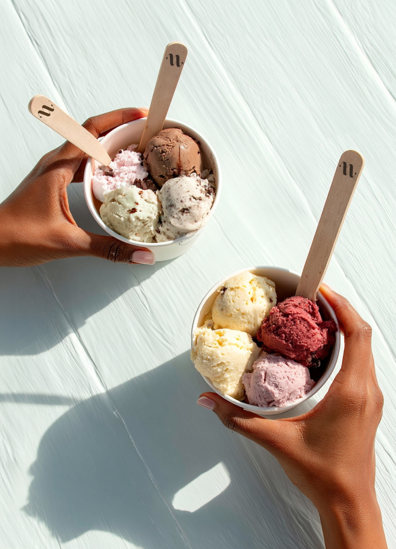 Two NUANCE gelato cups held over a sunlit wooden table